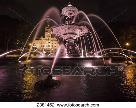 Stock Image - Quebec City's parliament building with water fountains illuminated at nighttime; Quebec City, Quebec, Canada. Fotosearch