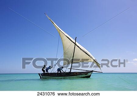 Stock Photograph - Raising the sail on a boat on the Indian Ocean; Vamizi Island, Mozambique. Fotosearch