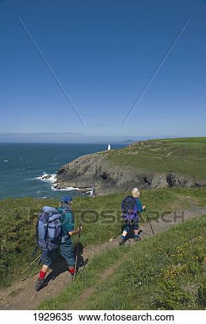 Stock Photography - Ramblers walking the Pembrokeshire Coastal path. Portgain Harbour. Pembrokeshire. Wales. Cymru. UK. United Kingdom.. Fotosearch