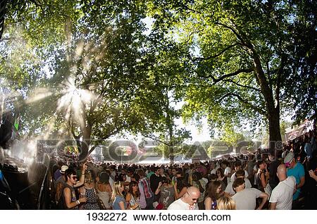 Stock Image - Rays Of Sunlight Coming Through The Trees Over Clubbers At Lovebox Festival In Victoria Park, London, Uk. Fotosearch