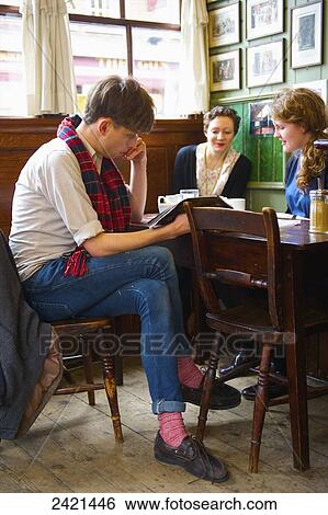 Stock Photograph - Reading and visiting in a cafe, Spitalfields; London, England. Fotosearch