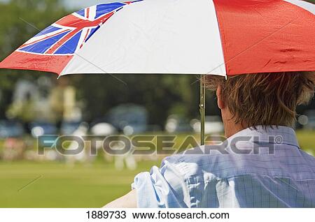 Stock Image - Rear View Of A Spectator With An Umbrella Watching A Cricket Match On A Hot Summers Day At Hastings.. Fotosearch
