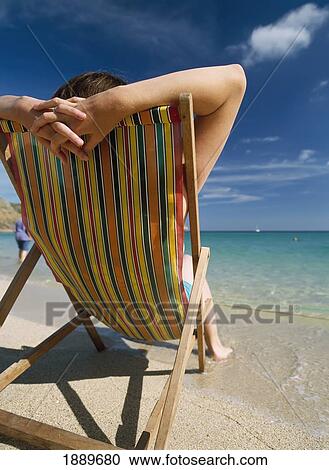 Rear View Of A Woman Relaxing In A Deck Chair, Beside The Sea At Porthcurno Beach. View Large Photo Image Stock Image - Rear View Of A Woman Relaxing In A Deck Chair, Beside The Sea At Porthcurno Beach.. Fotosearch
