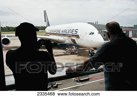 Stock Photo - Rear View Of Men Standing In Airport; Singapore. Fotosearch