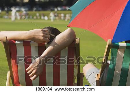 Picture - Rear View Of Spectators In Deck Chairs Watching A Cricket Match On A Hot Summers Day At Hastings.. Fotosearch