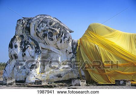 Stock Image - Reclining Budda statue wrapped with yellow cloth. Fotosearch