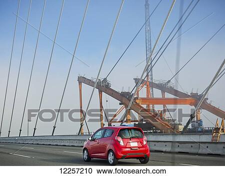 Stock Image - Red car crossing a bridge; British Columbia, Canada. Fotosearch
