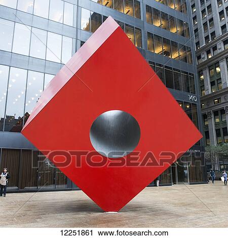 Stock Image - Red Cube sculpture outside a building; New York City, New York United States of America. Fotosearch