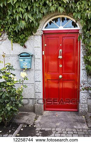 Picture - Red door with stone entrance, metal mailbox framed with green ivy; Adare, County Limerick, Ireland. Fotosearch