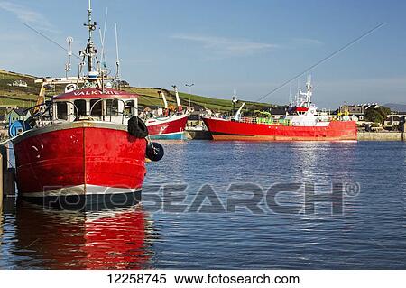 Stock Photography - Red fishing boats in a harbour with blue sky; Dingle, County Kerry, Ireland. Fotosearch