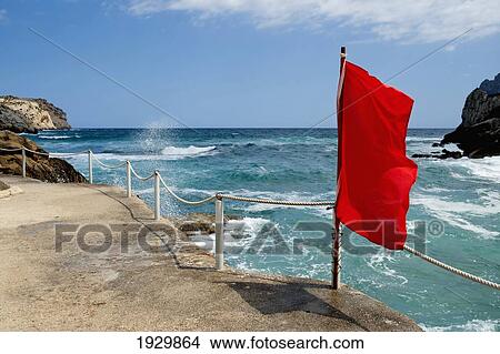Red Flag Waving In Cala Sant Vicenc, Mallorca, Balearic Islands, Spain View Large Photo Image Picture - Red Flag Waving In Cala Sant Vicenc, Mallorca, Balearic Islands, Spain. Fotosearch