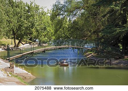 Stock Photo - Red Kayak Under A Footbridge In A City Park; Mendoza Argentina. Fotosearch