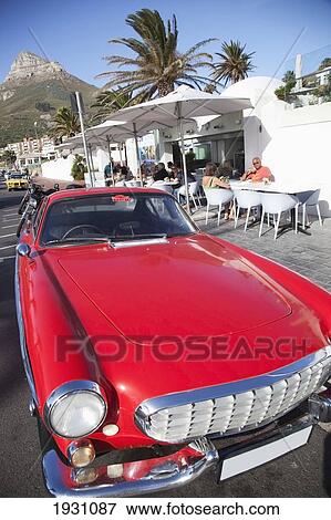 Stock Photo - Red Sports Car Parked In Camp's Bay In Cape Town; Bright, Cool Cars Parked In Camp's Bay, Cape Town, South Africa&#13; &#10. Fotosearch