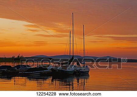 Stock Photo - Red sunset over a lake with boats; Knowlton, Quebec, Canada. Fotosearch
