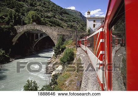 Stock Photograph - Red Train On Bend By Stream And Bridge. Fotosearch