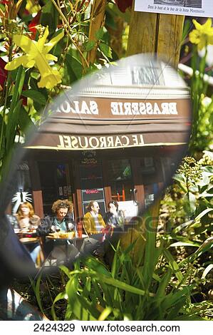 Stock Photo - Reflection in a car's side mirror of customer's sitting on the outdoor patio of a cafe; Paris, France. Fotosearch