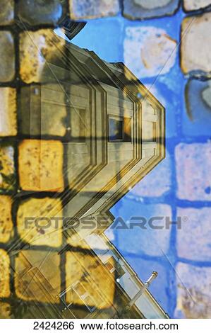 Stock Photograph - Reflection in glass of a residential building and pavers on a walkway, Marais district; Paris, France. Fotosearch