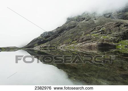 Stock Photograph - Reflections in perfectly still small lake below Sgurr Dearg and Sgurr Alasdair in the Black Cuillin; Isle of Skye, Scotland. Fotosearch