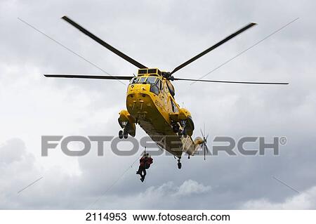 Stock Image - Rescue Workers Hang From A Helicopter In Mid-Air; Northumberland England. Fotosearch