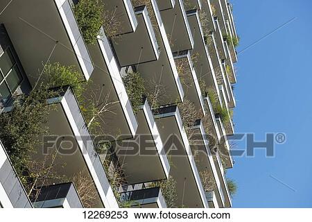 Stock Image - Residential building with plants on balconies; Milan, Lombardy, Italy. Fotosearch