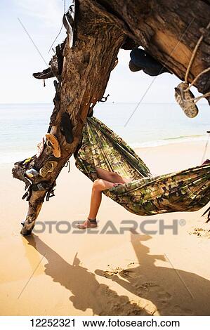 Stock Image - Resting in a hammock in a tree decorated with lost flip flops; Sihanoukville, Cambodia. Fotosearch