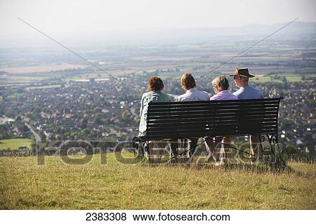 Stock Photo - Resting on a bench and admiring the view at Cleeve Hill, the highest point in the Cotswolds on the famous National Trail 100 mile Cotswold Way trail above Cheltenham; Gloucestershire, England. Fotosearch