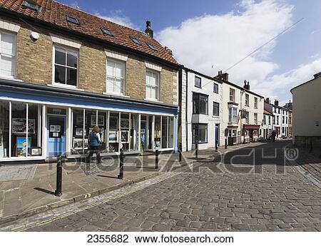 Stock Image - Retail Shops And Housing Along A Cobbled Street; Staithes, Yorkshire, England. Fotosearch