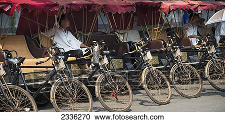 Rickshaws And A Driver Parked In A Row In Hutong District; Beijing, China View Large Photo Image Stock Image - Rickshaws And A Driver Parked In A Row In Hutong District; Beijing, China. Fotosearch
