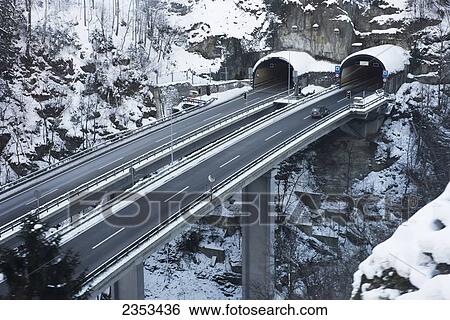 Stock Photograph - Roads And Tunnels Side By Side Leading Into And Out Of A Mountainside; Uri, Switzerland. Fotosearch