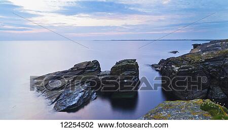 Rock and tranquil water along the coastline at dawn; Orkney, Scotland View Large Photo Image Stock Image - Rock and tranquil water along the coastline at dawn; Orkney, Scotland. Fotosearch