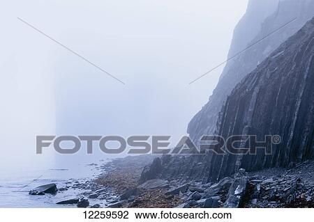 Stock Image - Rock cliff in the fog; Perce, Gaspesie, Quebec, Canada. Fotosearch