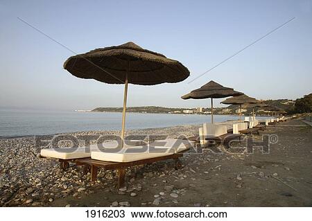 Stock Image - Row Of Sun Umbrellas And Loungers. Fotosearch