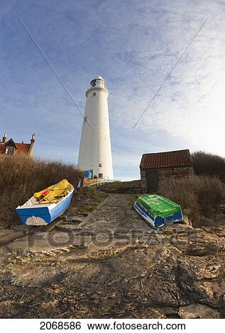 Rowboats Abandoned On The Shore In Front Of The Lighthouse On St. Mary's Island; Northumberland England View Large Photo Image Stock Photograph - Rowboats Abandoned On The Shore In Front Of The Lighthouse On St. Mary's Island; Northumberland England. Fotosearch