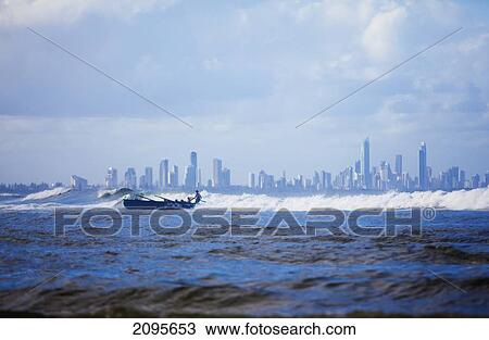 Stock Image - Rowing A Boat In A Large Wave At Surfer's Paradise; Gold Coast Queensland Australia. Fotosearch