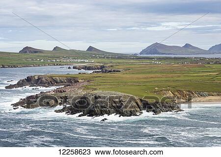 Rugged coastline with waves and flat grassland and mountains in the distance; Ballinglanna, County Cork, Ireland View Large Photo Image Stock Image - Rugged coastline with waves and flat grassland and mountains in the distance; Ballinglanna, County Cork, Ireland. Fotosearch