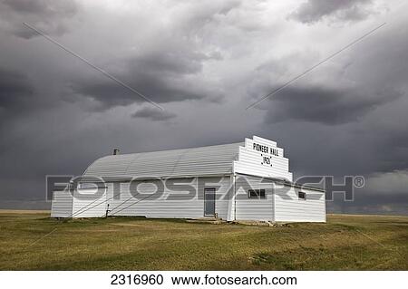 Stock Image - Rural Community Hall Under Dark Storm Clouds; Saskatchewan Canada. Fotosearch