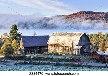 Stock Image - Rustic buildings and barn among autumn colors at sunrise; Blanche, Outaouais, Quebec, Canada. Fotosearch