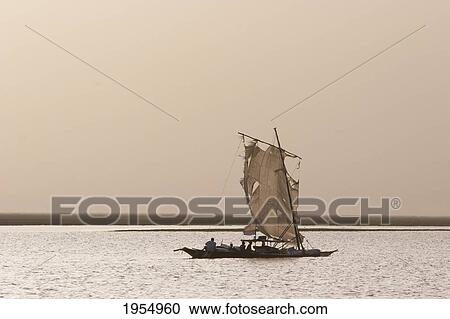 Stock Image - Sail boat in the sunset on Lake Debo, formed by the seasonal flooding of the Niger River, Mali. Fotosearch
