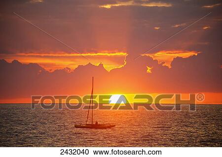 Stock Image - Sailboat at sunset off of the Kihei Wailea beach area; Kihei, Maui, Hawaii, United States of America. Fotosearch