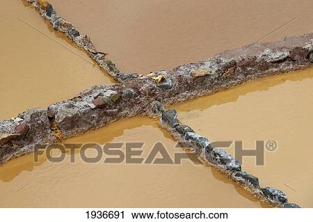 Stock Image - Salt Pans Reflected In The Water; Maras Peru. Fotosearch
