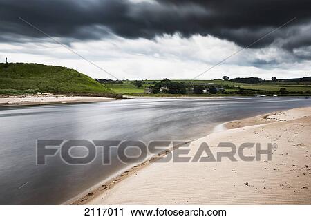 Stock Image - Sand Beach Along A River With Storm Clouds; Alnmouth Northumberland England. Fotosearch