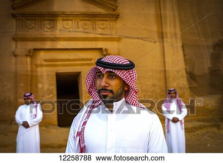 Stock Photo - Saudi men standing at pre-Islamic archaeological site; Madain Saleh, Saudi Arabia. Fotosearch