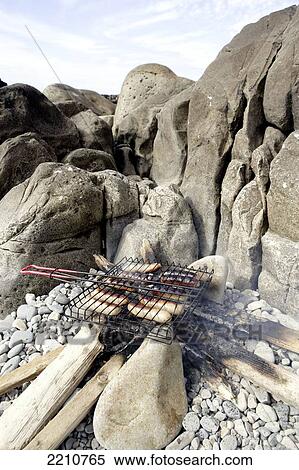 Stock Photography - Sausages Cooking Over A Driftwood Beach Fire. Ireland.. Fotosearch