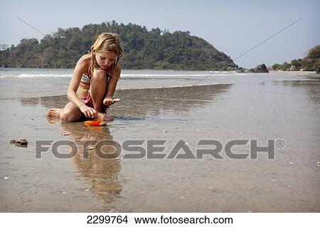 Picture - Savanna Rollason collects shells on Palolem beach, Goa, India.. Fotosearch