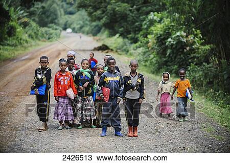 Stock Image - School children on their way to school on rough roads in Highlands of Ethiopia; Ethiopia. Fotosearch