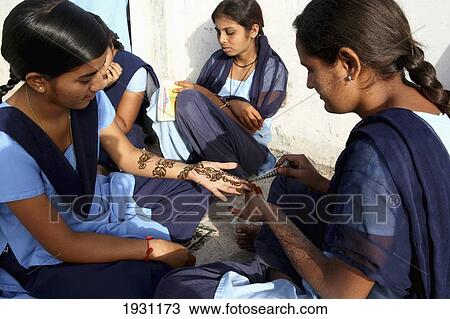 Stock Image - School girls putting mehendi/mehndi, the application of henna, on each other's hands and arms. Village of Run, in countryside south of Ahmedabad City, Gujurat State, India., Village of Run, in countryside south of Ahmedabad City, Gujurat State, India.. Fotosearch