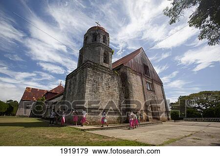 Stock Photo - Schoolchildren Walk Past The Historic San Antonio De Padua Church; Lazi, Siquijor, Philippines. Fotosearch