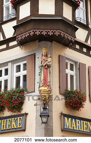 Stock Image - Sculpture Of A Female Figure Holding A Baby On The Corner Of A Building; Rothenburg Ob Der Tauber Bavaria Germany. Fotosearch