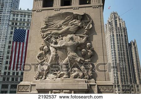 Sculpture On A Wall With Skyscrapers In The Background Against A Blue Sky; Chicago Illinois United States Of America View Large Photo Image Stock Photo - Sculpture On A Wall With Skyscrapers In The Background Against A Blue Sky; Chicago Illinois United States Of America. Fotosearch