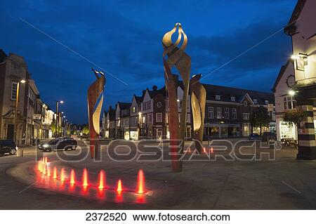 Stock Image - Sculptures illuminated at dusk along a city street; Hertfordshire, England. Fotosearch